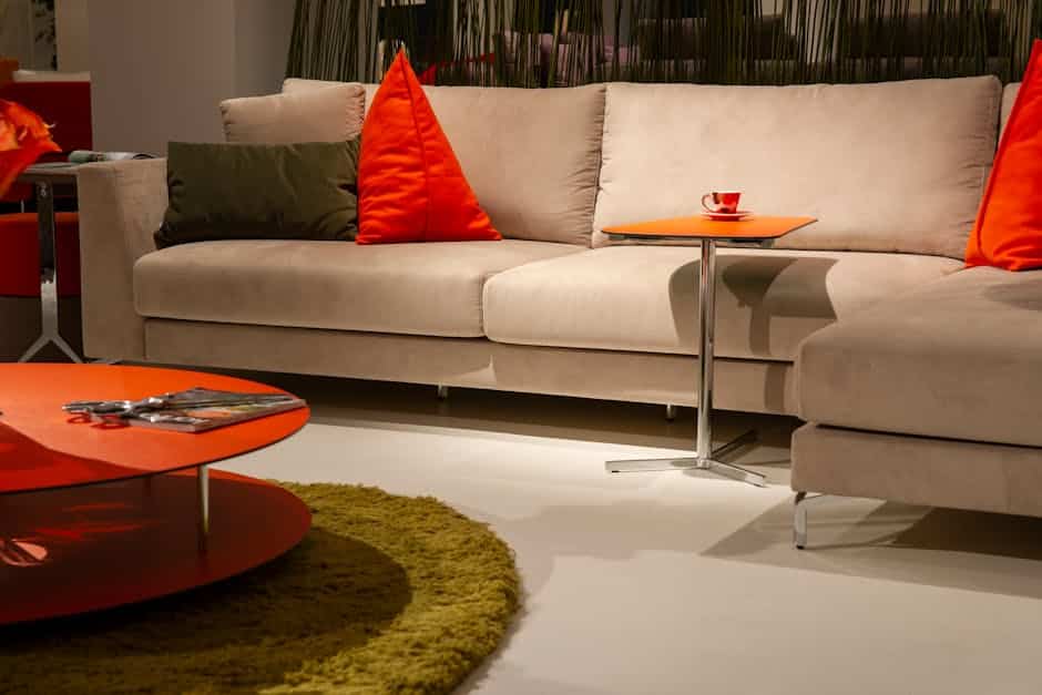 Salon contemporain, canapé d'angle beige réveillé par des touches de couleur orange et un tapis vert olive