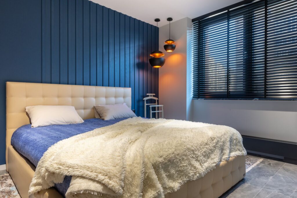 Idées déco chambre : tête de lit capitonnée, mur bleu profond et plaid douillet pour un cocon reposant
