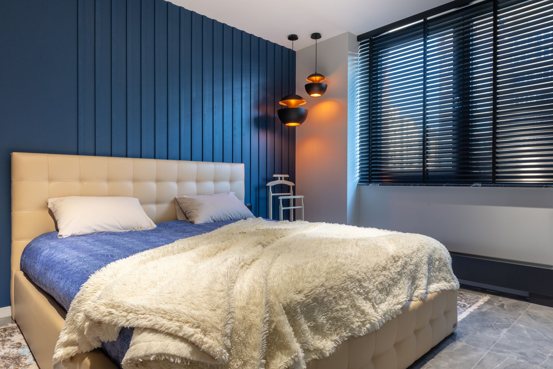 Idées déco chambre : tête de lit capitonnée, mur bleu profond et plaid douillet pour un cocon reposant